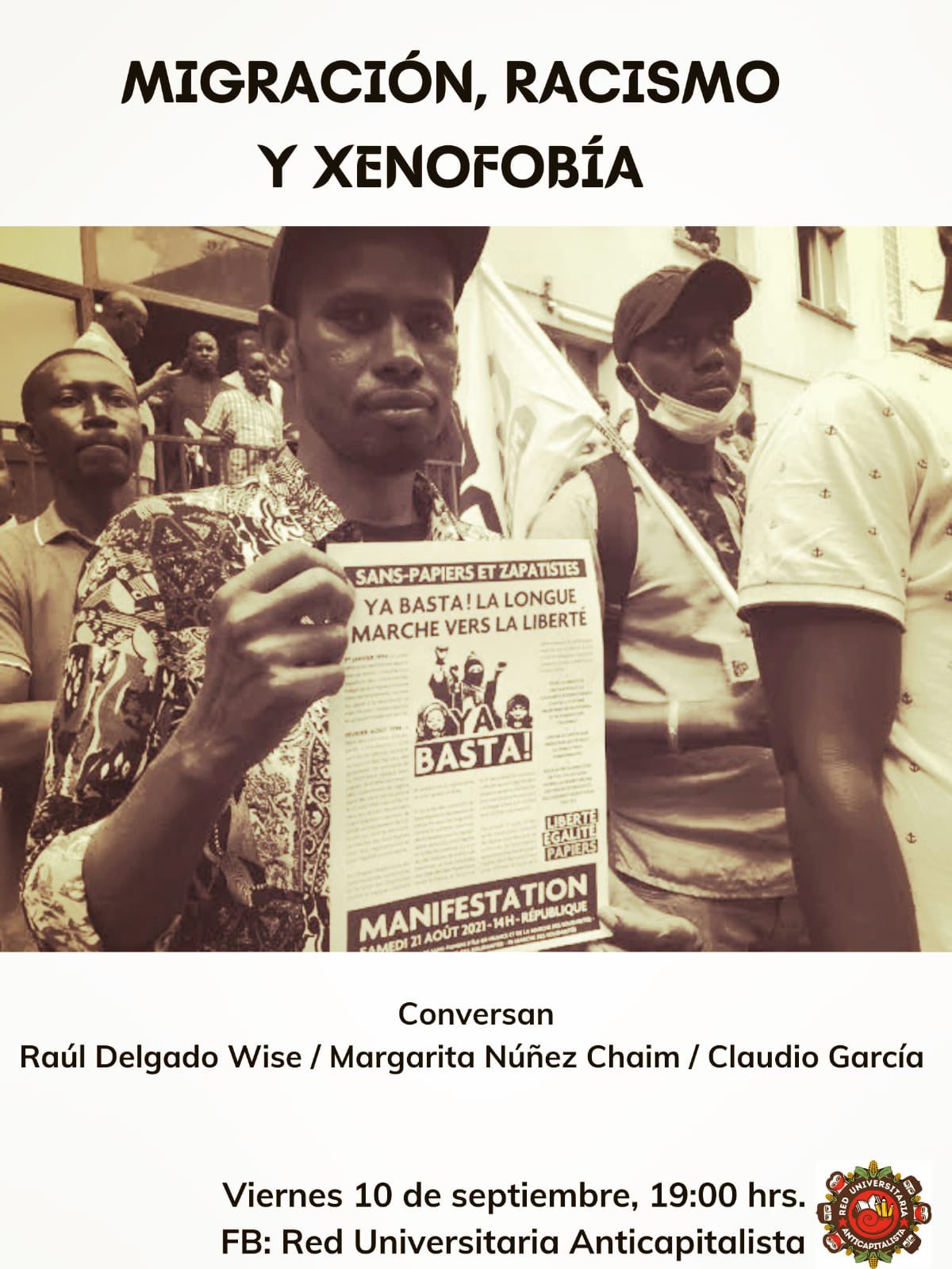 Imagen color sepia se ve a varias personas de origen africano, una de ellas que mira a la camara está sosteniendo un cartel en frances que dice "sans-papiers et zapatistes. Ya Basta! La Longue marche vers la Liberté"